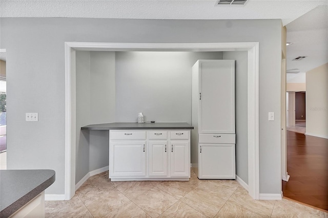 kitchen featuring white cabinetry, dark countertops, visible vents, and baseboards