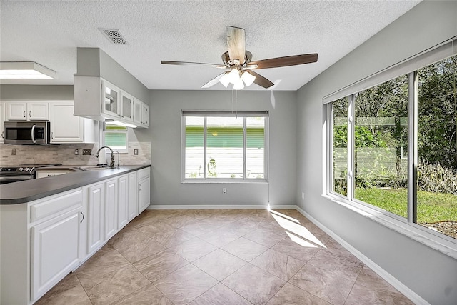 kitchen with visible vents, a sink, tasteful backsplash, dark countertops, and stainless steel appliances