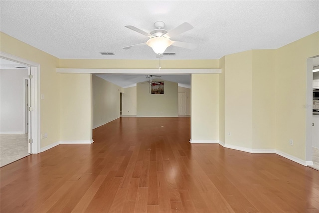 spare room with ceiling fan, visible vents, a textured ceiling, and wood finished floors