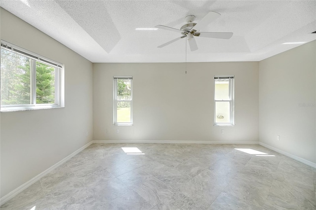 unfurnished room with a ceiling fan, baseboards, and a textured ceiling