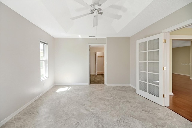 empty room with visible vents, baseboards, a tray ceiling, and a ceiling fan