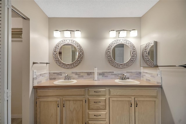 full bathroom with a textured ceiling, backsplash, and a sink