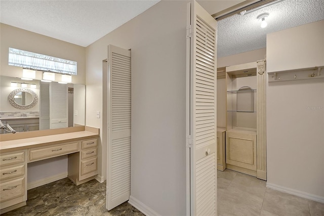 bathroom with a closet, baseboards, a textured ceiling, and vanity