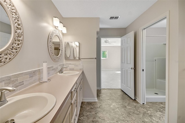 full bath featuring visible vents, a textured ceiling, walk in shower, and a sink