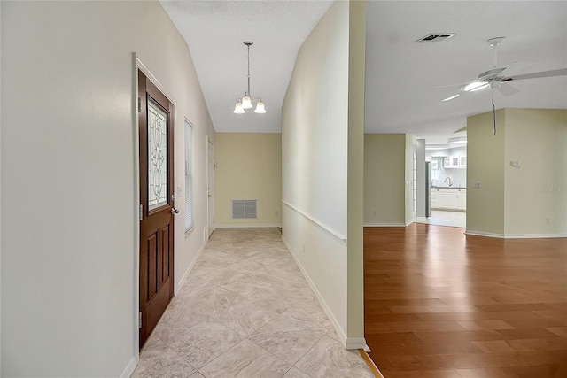 corridor featuring lofted ceiling, visible vents, and a chandelier