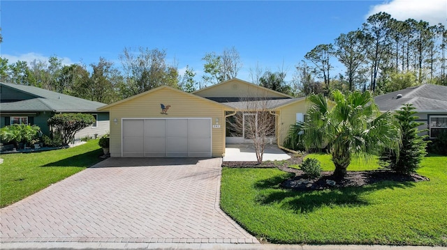 single story home with a front lawn, decorative driveway, and a garage