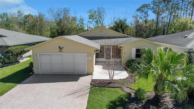 view of front of property with decorative driveway, a front lawn, roof with shingles, and an attached garage