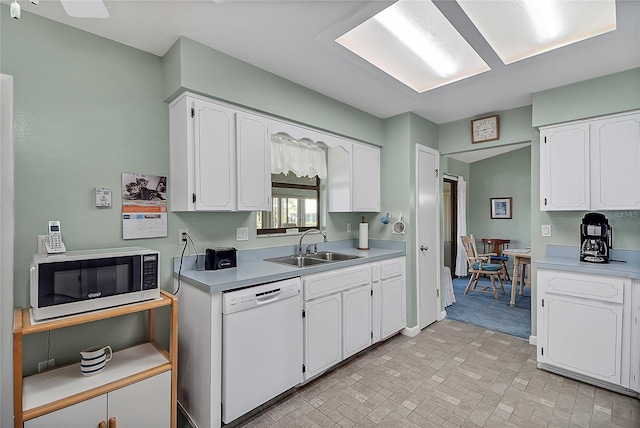 kitchen with a sink, light countertops, white cabinets, dishwasher, and stainless steel microwave