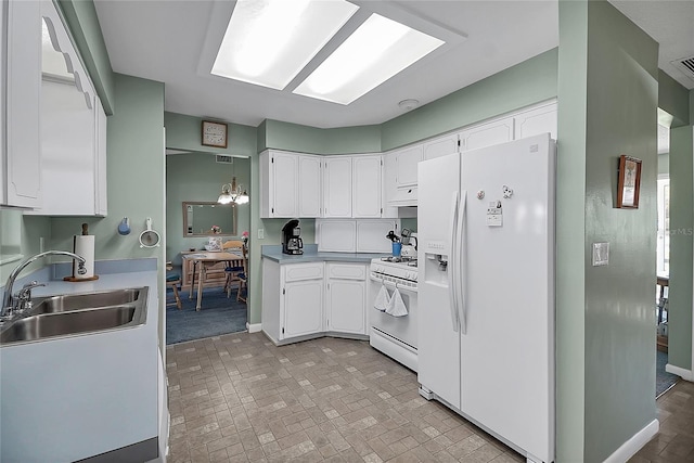 kitchen featuring white appliances, brick floor, a sink, light countertops, and white cabinets