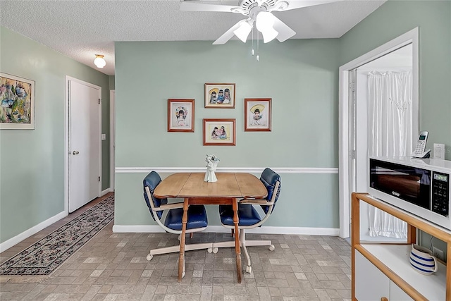 dining room featuring brick floor, baseboards, a textured ceiling, and ceiling fan