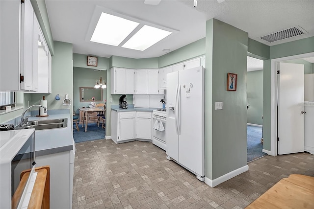 kitchen featuring white appliances, baseboards, visible vents, a sink, and white cabinets