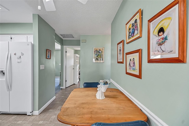 hall featuring baseboards, visible vents, and a textured ceiling