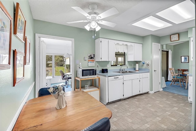 kitchen featuring a sink, white cabinets, light countertops, baseboards, and dishwasher