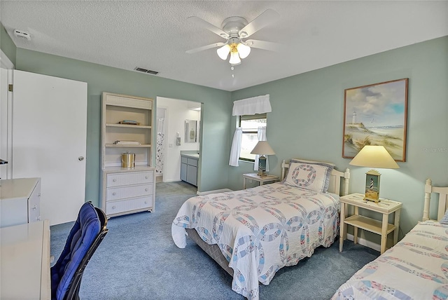 bedroom featuring a ceiling fan, carpet, visible vents, ensuite bath, and a textured ceiling