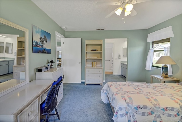 bedroom with ensuite bathroom, a textured ceiling, and carpet flooring