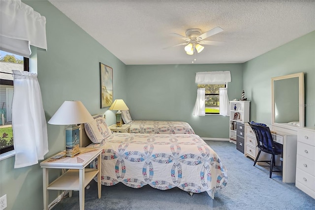 carpeted bedroom with ceiling fan and a textured ceiling