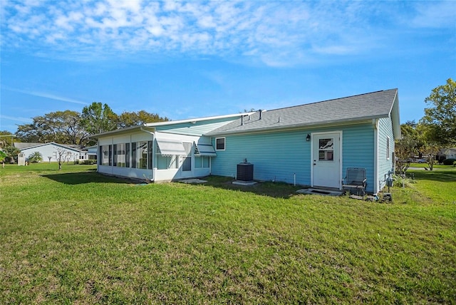 rear view of property featuring central AC unit and a yard