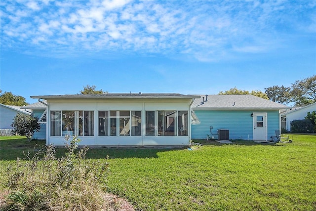 rear view of property featuring central air condition unit, a lawn, and a sunroom