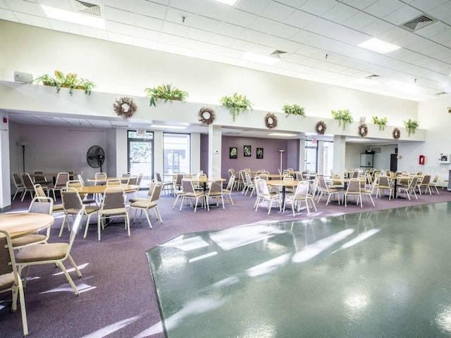 dining space with visible vents, a paneled ceiling, and a high ceiling