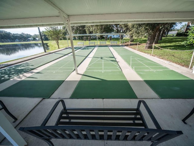 view of community with shuffleboard, a yard, and a water view