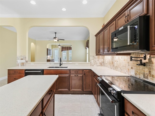 kitchen featuring light countertops, black appliances, ceiling fan, arched walkways, and a sink