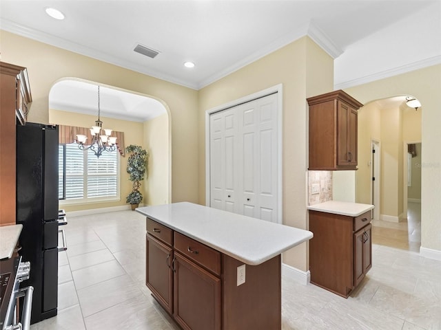 kitchen featuring arched walkways, visible vents, light countertops, and freestanding refrigerator