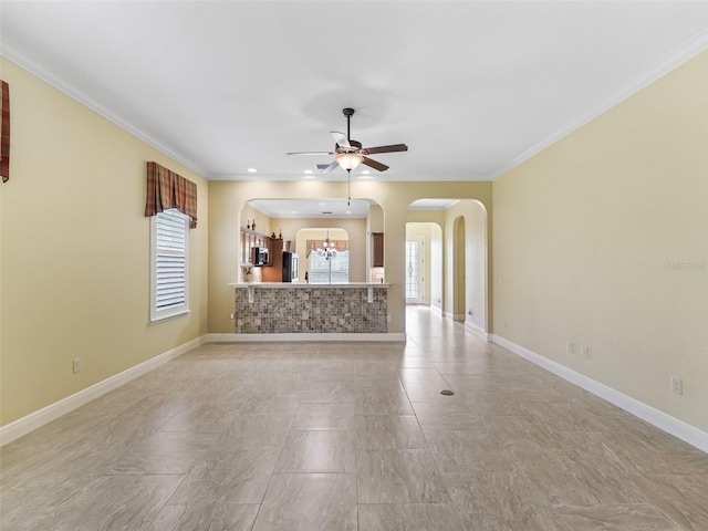 unfurnished living room featuring arched walkways, plenty of natural light, and ceiling fan with notable chandelier