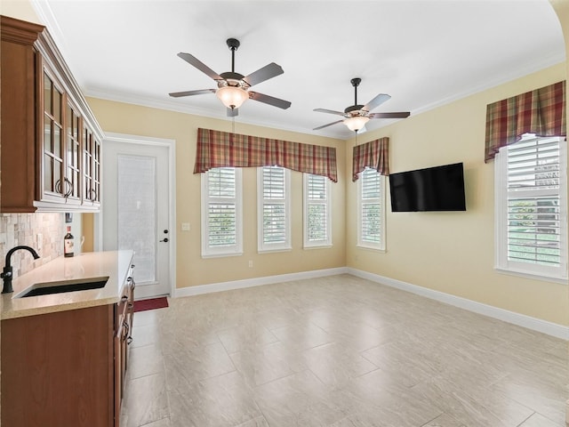 kitchen featuring glass insert cabinets, baseboards, a sink, a ceiling fan, and backsplash
