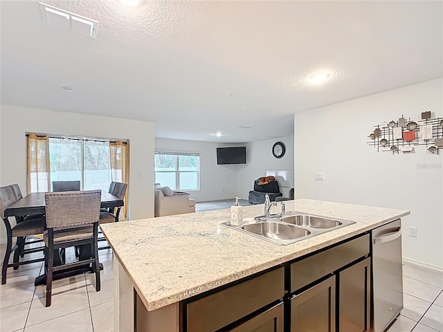 kitchen featuring visible vents, a kitchen island with sink, a sink, open floor plan, and dishwasher