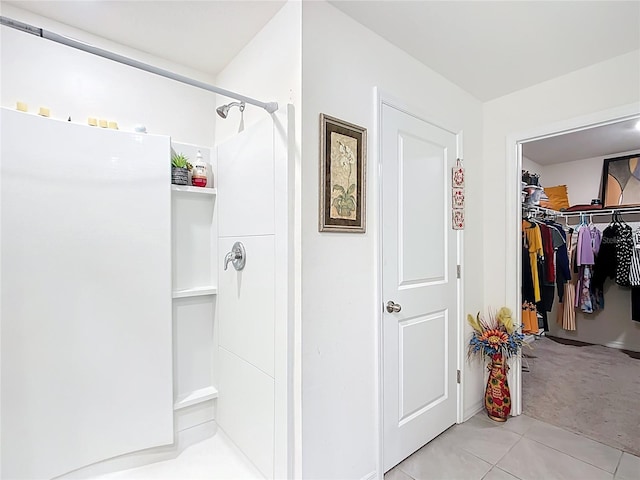 full bath featuring tile patterned floors, walk in shower, and a spacious closet