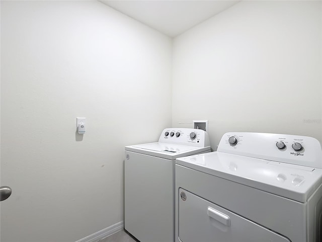 washroom with baseboards, laundry area, and washer and clothes dryer