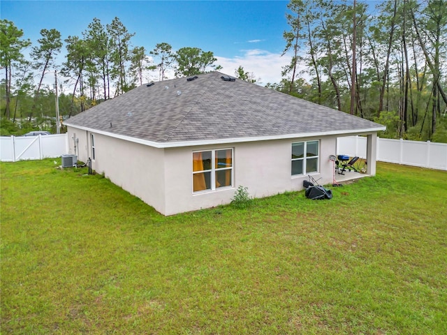 back of property featuring a fenced backyard, a lawn, and roof with shingles