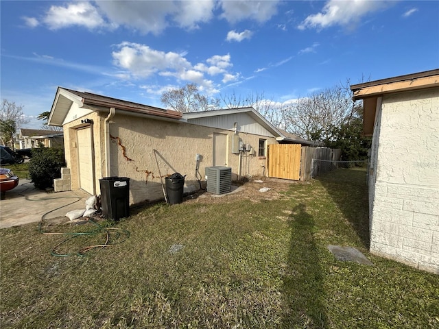 view of home's exterior with a yard, central AC unit, fence, and stucco siding