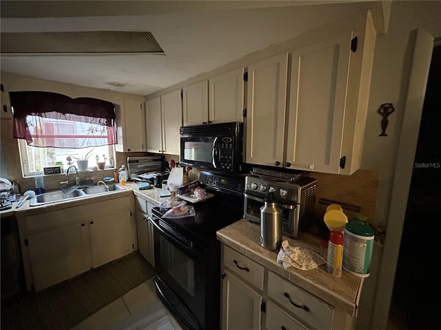 kitchen with black appliances, white cabinets, light countertops, and a sink