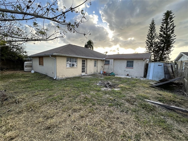 back of property with cooling unit, a lawn, and stucco siding