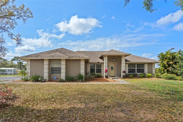 view of front of house with stucco siding and a front lawn