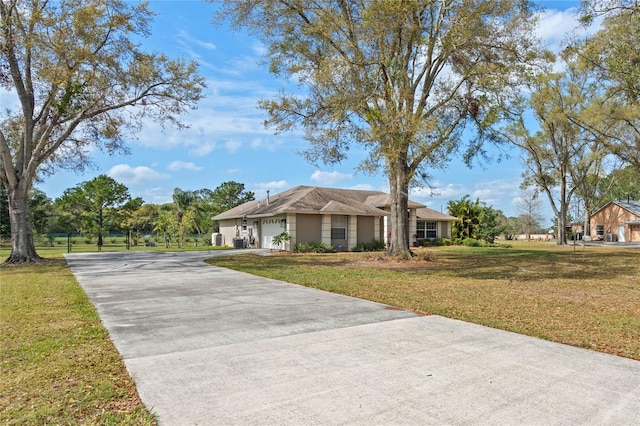 single story home with a front yard, an attached garage, and concrete driveway