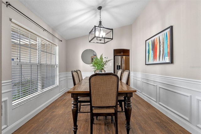 dining area featuring dark wood finished floors, a decorative wall, a notable chandelier, and a wainscoted wall