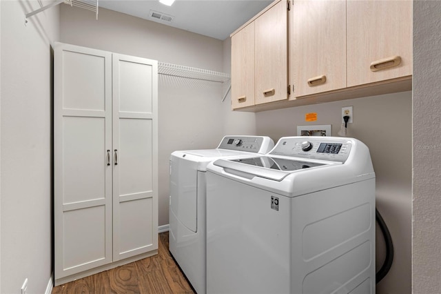 washroom featuring washer and dryer, visible vents, cabinet space, and light wood-style flooring