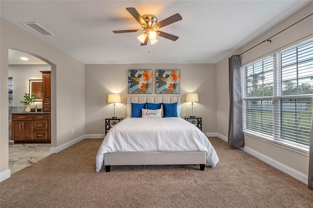 bedroom featuring baseboards, arched walkways, visible vents, and light carpet