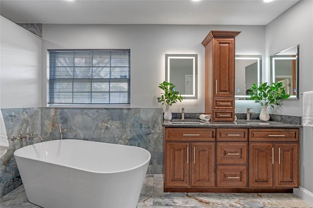 bathroom featuring double vanity, a freestanding tub, and a sink