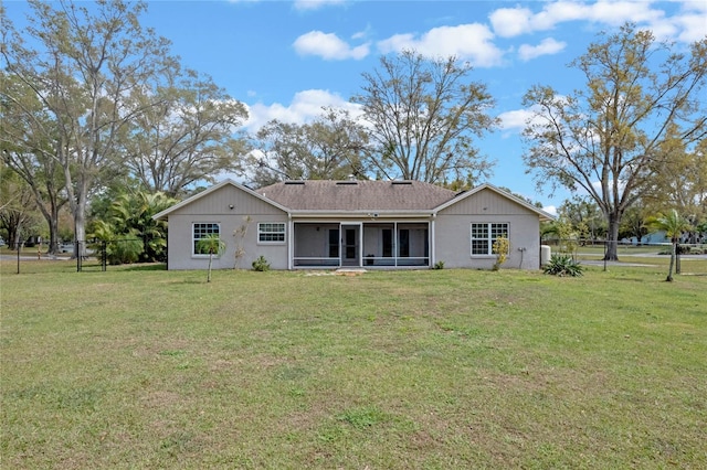 back of property with a lawn, fence, and a sunroom