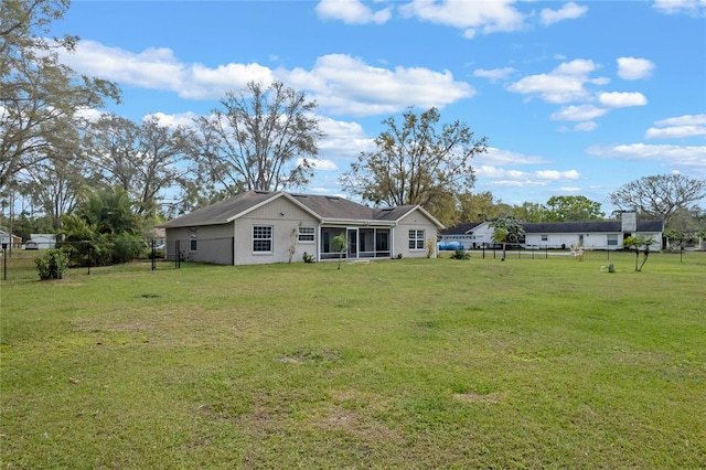 back of house featuring a lawn, fence, and a sunroom