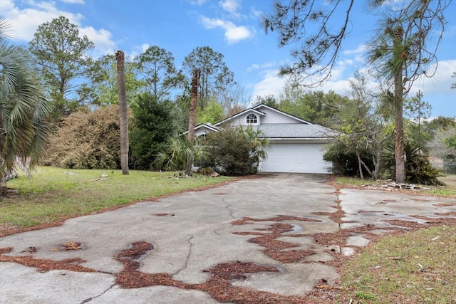 view of side of property with aphalt driveway, an attached garage, and a yard