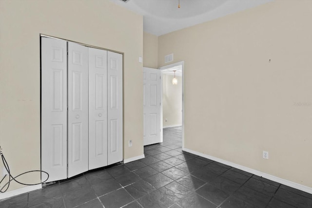 unfurnished bedroom featuring vaulted ceiling, baseboards, visible vents, and a closet