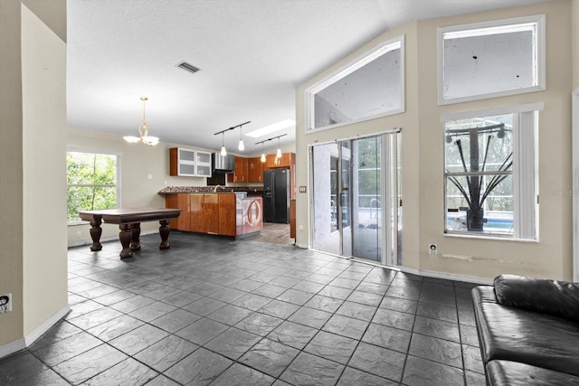 interior space featuring visible vents, an inviting chandelier, rail lighting, and baseboards