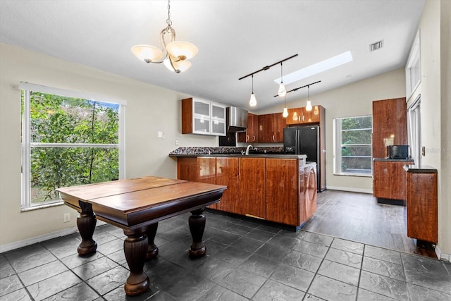 kitchen with brown cabinetry, visible vents, a peninsula, freestanding refrigerator, and dark countertops