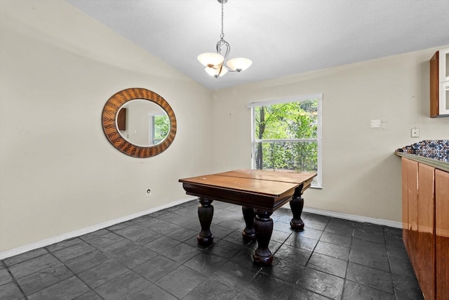 dining space with stone tile floors, a notable chandelier, baseboards, and lofted ceiling