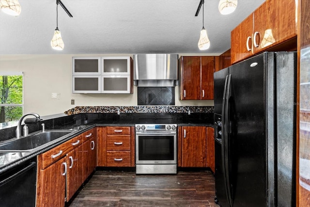 kitchen with dark wood-style floors, a sink, black appliances, pendant lighting, and wall chimney range hood