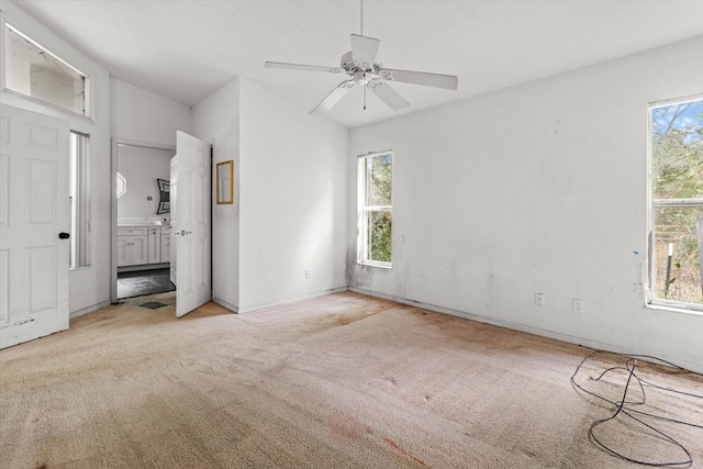 unfurnished bedroom with baseboards, ceiling fan, ensuite bath, and carpet